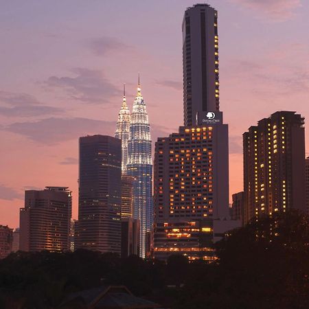 Doubletree By Hilton Kuala Lumpur Hotel Interior photo The photo showcases a city skyline at dusk, featuring tall buildings against a colorful sunset. Prominent in the image are two tower-like structures, which appear to be twin skyscrapers illuminated in a striking way, suggesting they might be iconic l