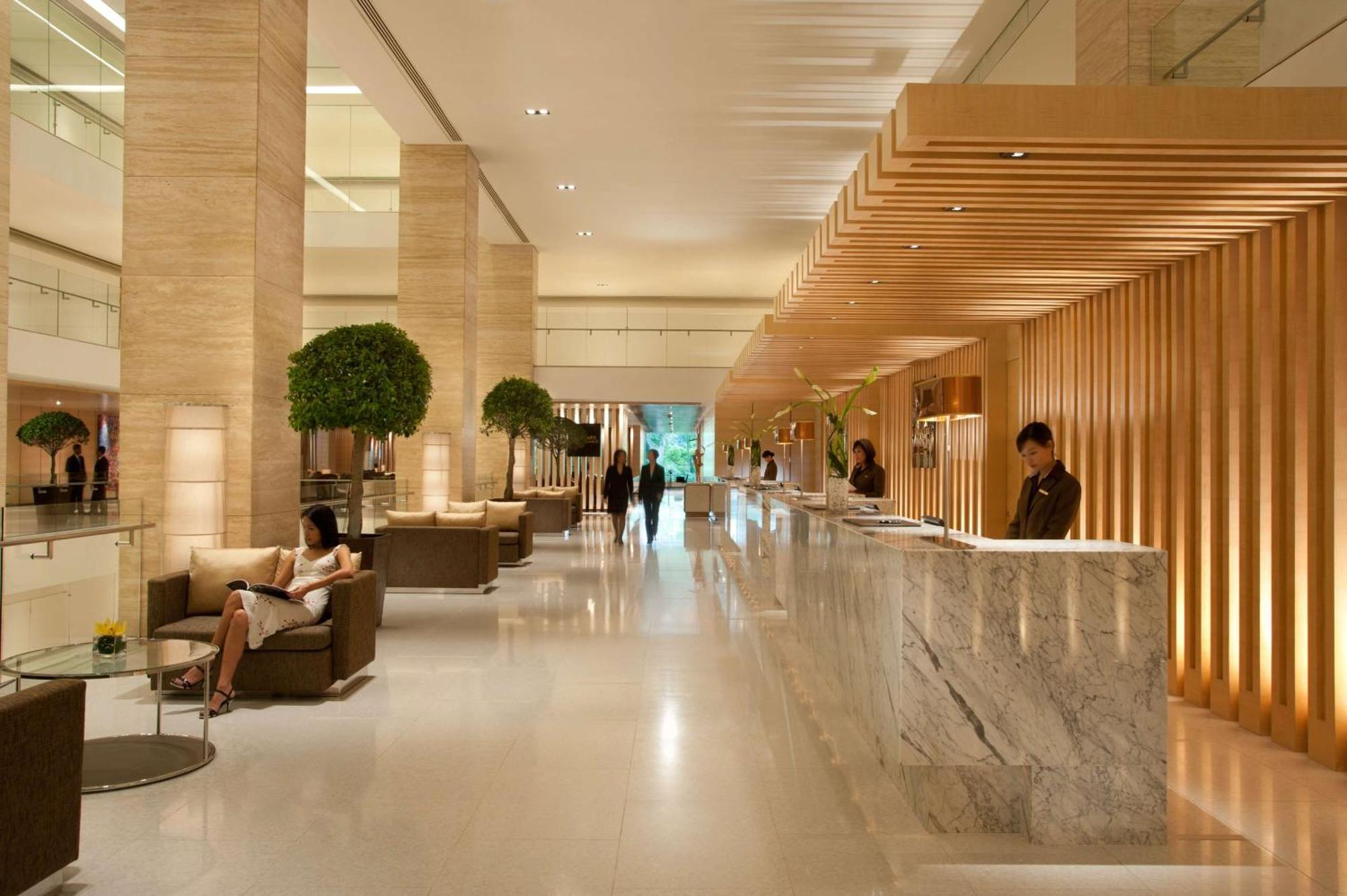 Doubletree By Hilton Kuala Lumpur Hotel Exterior photo The photo shows a modern hotel lobby. It features a spacious, well-lit area with high ceilings and elegant design elements. The reception desk, made of marble, is positioned prominently, with staff members attending to guests. There are several comfo