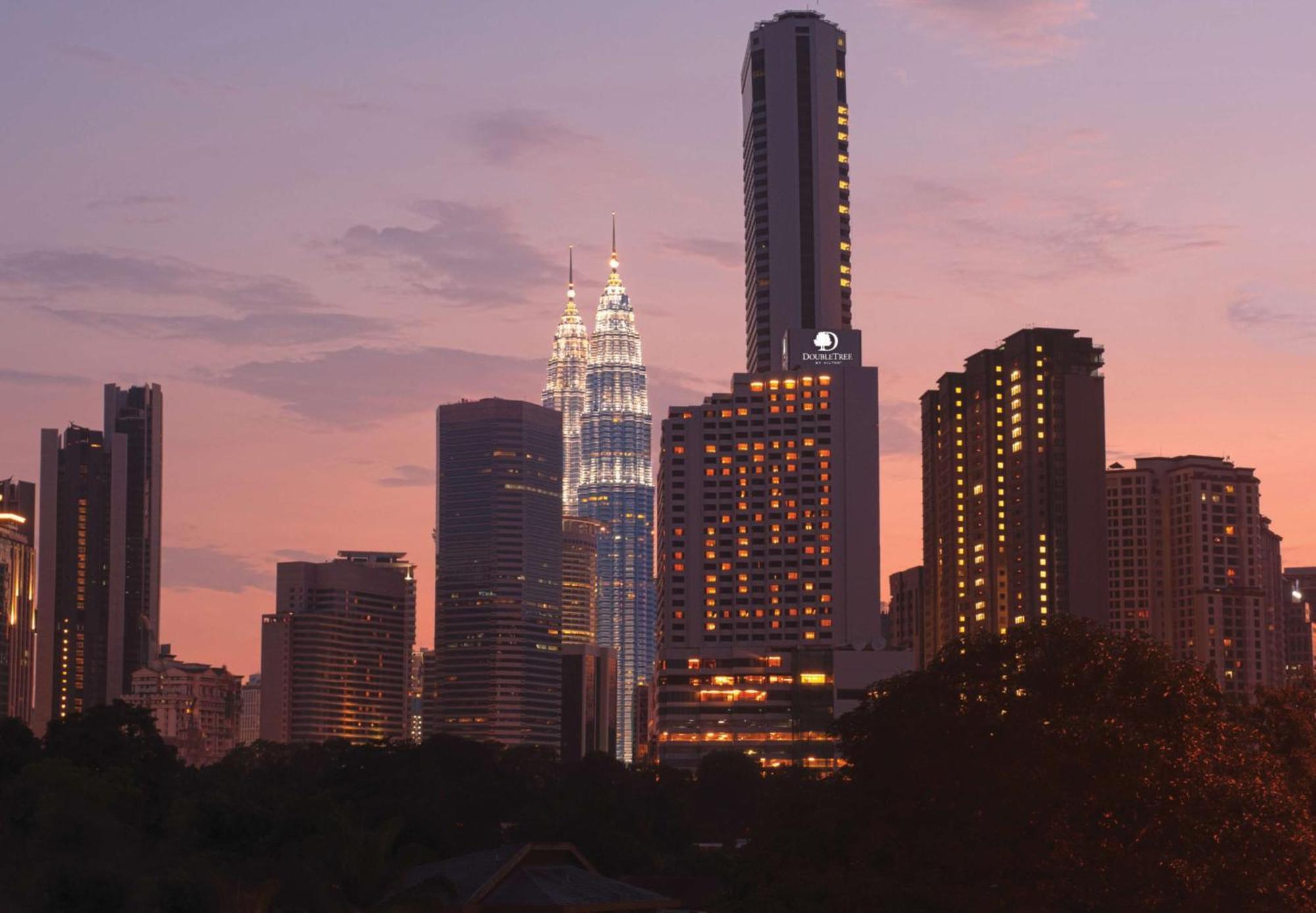 Doubletree By Hilton Kuala Lumpur Hotel Interior photo The photo showcases a city skyline at dusk, featuring tall buildings against a colorful sunset. Prominent in the image are two tower-like structures, which appear to be twin skyscrapers illuminated in a striking way, suggesting they might be iconic l